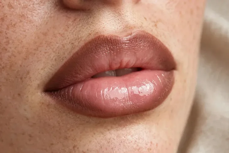 Ombre lip makeup technique with darker outer edges and glossy lighter center for fuller lips